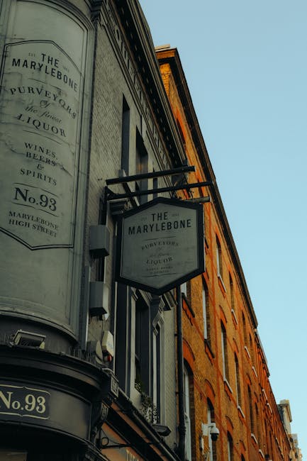 A close-up view of a traditional pub or shop sign mounted on the exterior of a narrow, brick-fronted building on Marylebone High Street, displaying the name 'The Marylebone' along with the address 'No
